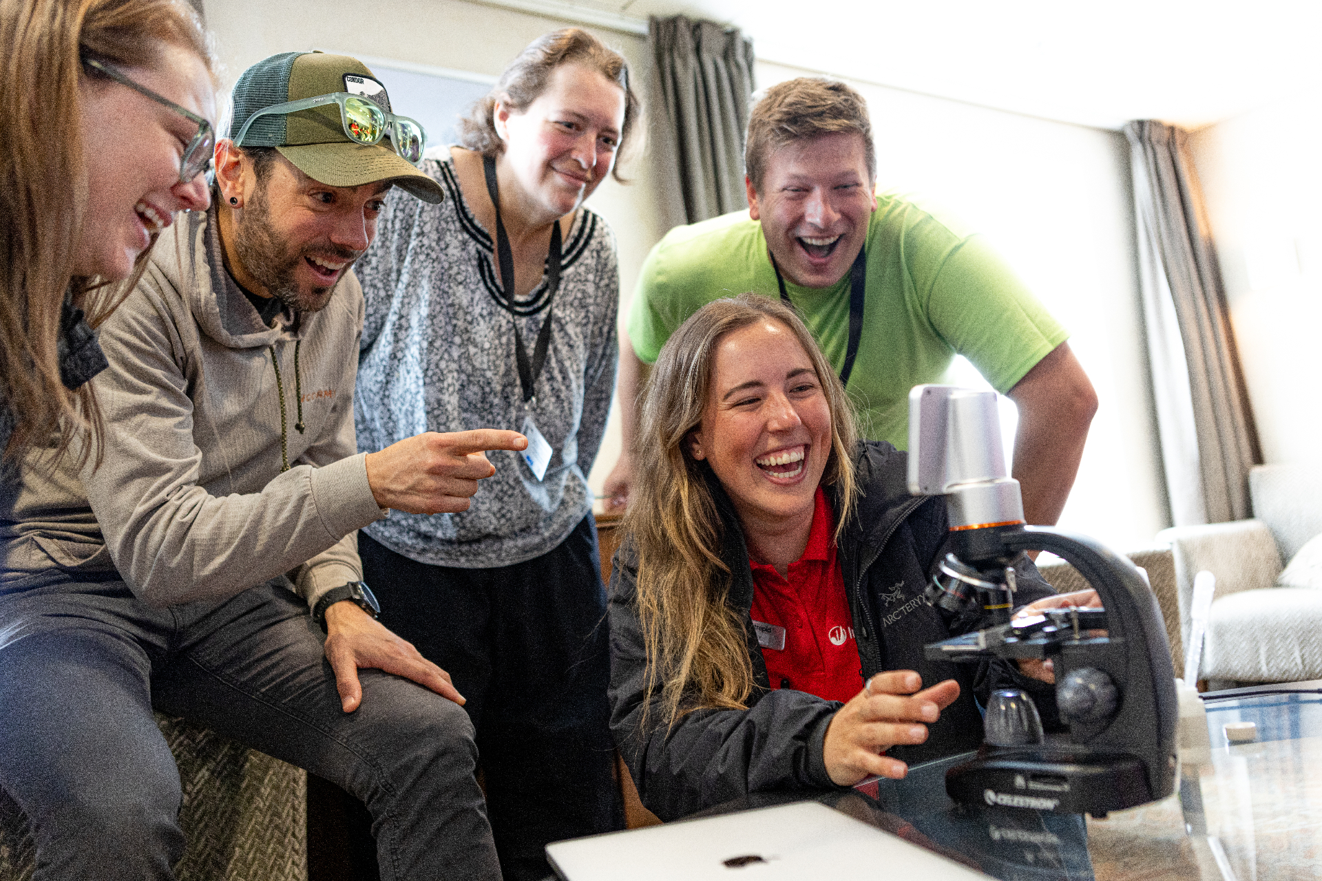 Travelers and facilitator laughing at the microscope while viewing live plankton samples onboard